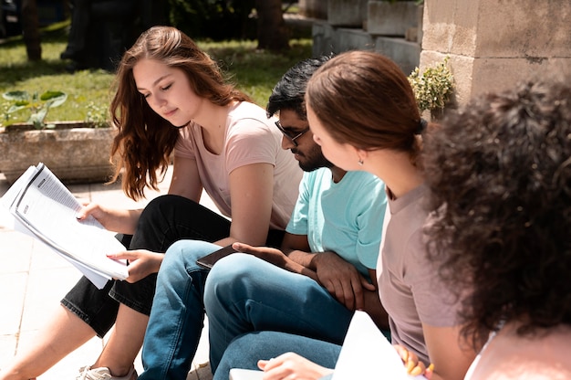 Compañeros que estudian juntos frente a su universidad antes de un examen