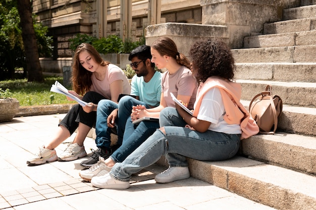 Compañeros que estudian juntos frente a su universidad antes de un examen