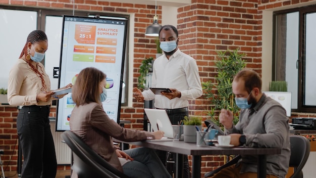 Compañeros de trabajo afroamericanos que muestran análisis financieros en exhibición, hacen presentaciones de gráficos en la oficina de reuniones. gente de negocios usando monitor para diseñar proyectos de marketing y estrategia.