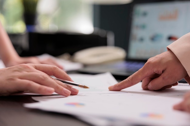 Compañeros de trabajo analizando el informe financiero sobre la reunión, de cerca en las manos, mujer señalando con el dedo en los gráficos. Concepto de trabajo en equipo de colegas, estrategia de proyecto de puesta en marcha de la empresa de planificación de empleados