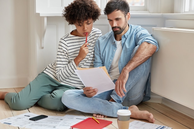 Compañeros de trabajo exitosos interraciales concentrados trabajan juntos en el informe económico anual