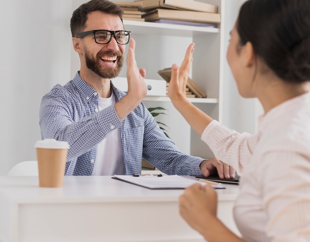 Compañeros de trabajo felices celebrando con choca esos cinco