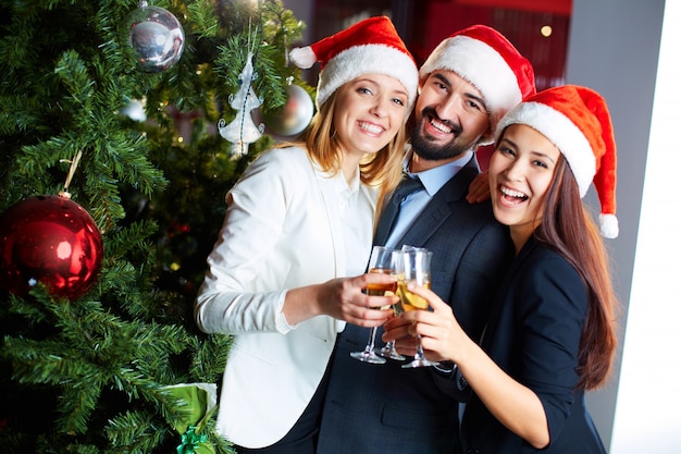 Compañeros de trabajo felices con champán celebrando la navidad