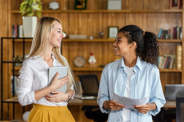Compañeros de trabajo femeninos sonrientes conversando en el trabajo