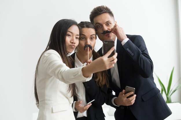 Compañeros de trabajo haciendo foto con accesorio bigote
