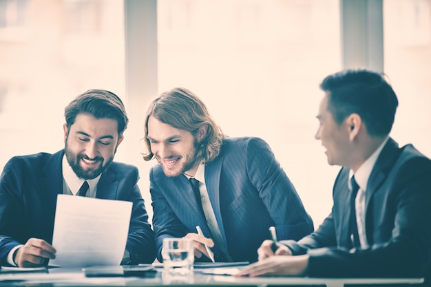 Compañeros de trabajo leyendo un documento y riendo