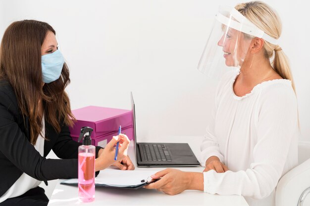 Compañeros de trabajo con máscara médica y protector facial