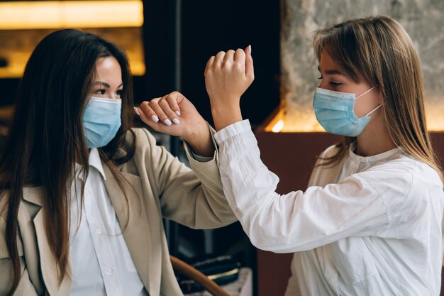 Compañeros de trabajo en máscaras protectoras dando cinco con los codos