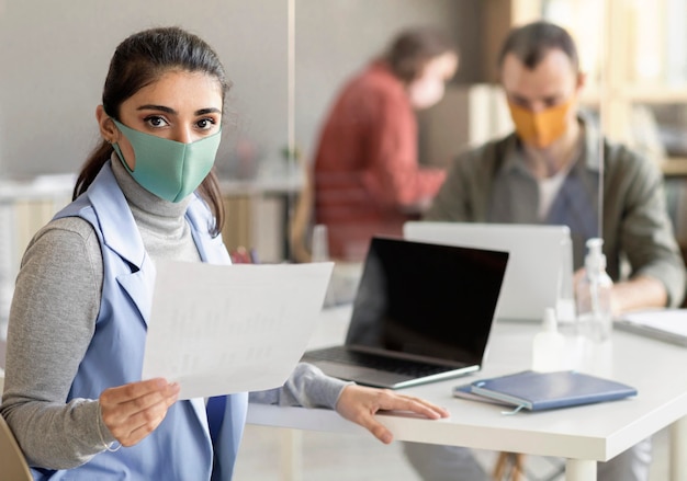 Foto gratuita compañeros de trabajo con mascarilla en la oficina