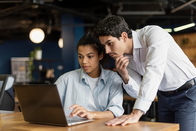 Compañeros de trabajo masculinos y femeninos en la oficina trabajando con ordenador portátil