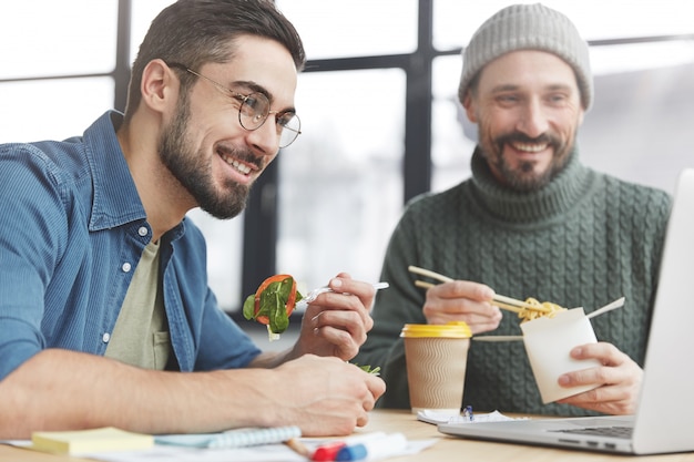 Compañeros de trabajo masculinos en la oficina con almuerzo