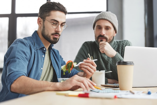 Compañeros de trabajo masculinos en la oficina con almuerzo