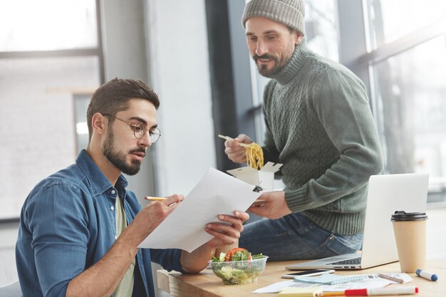 Compañeros de trabajo masculinos en la oficina con almuerzo