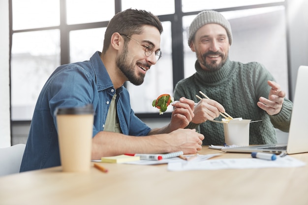 Compañeros de trabajo masculinos en la oficina con almuerzo