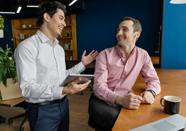 Foto gratuita compañeros de trabajo masculinos sonrientes que tienen una conversación en el trabajo