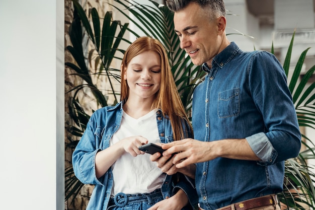 Foto gratuita compañeros de trabajo mirando un teléfono en la oficina