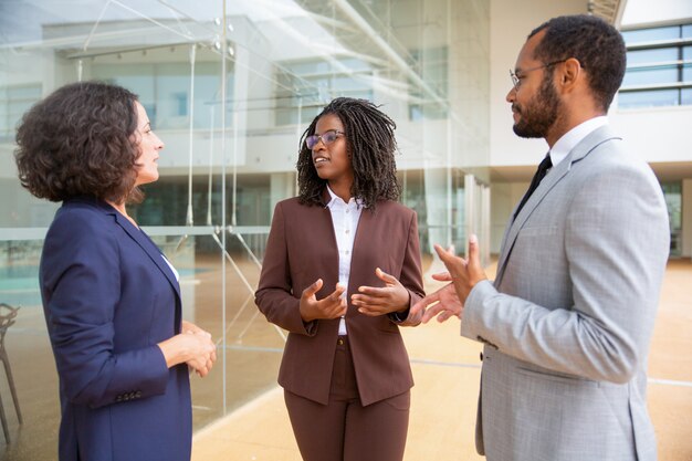 Compañeros de trabajo multiétnicos de pie y hablando