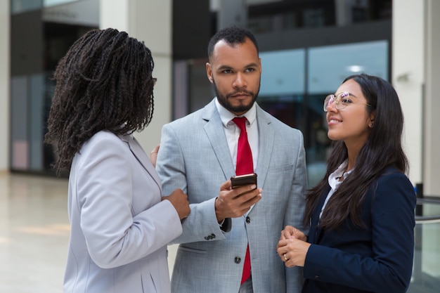 Compañeros de trabajo multiétnicos con teléfono inteligente