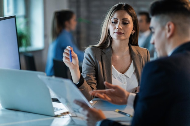 Compañeros de trabajo de negocios que cooperan mientras revisan el papeleo y analizan los planes de negocios en el trabajo El foco está en la mujer