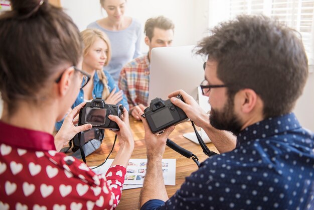 Compañeros de trabajo en la oficina con cámaras fotográficas y una computadora