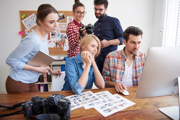 Compañeros de trabajo en la oficina con cámaras fotográficas y una computadora