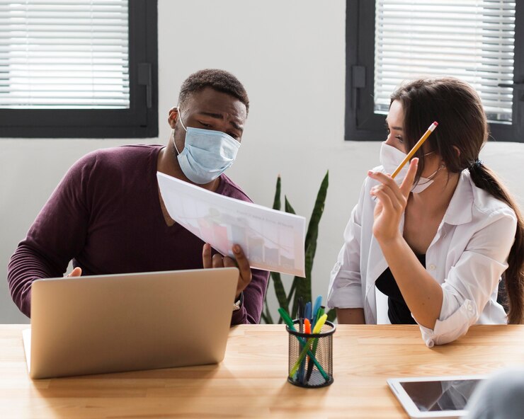 Foto gratuito compañeros de trabajo en la oficina durante la pandemia con máscaras médicas