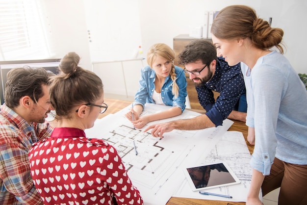 Foto gratuita compañeros de trabajo en la oficina con planos de arquitectura y una computadora