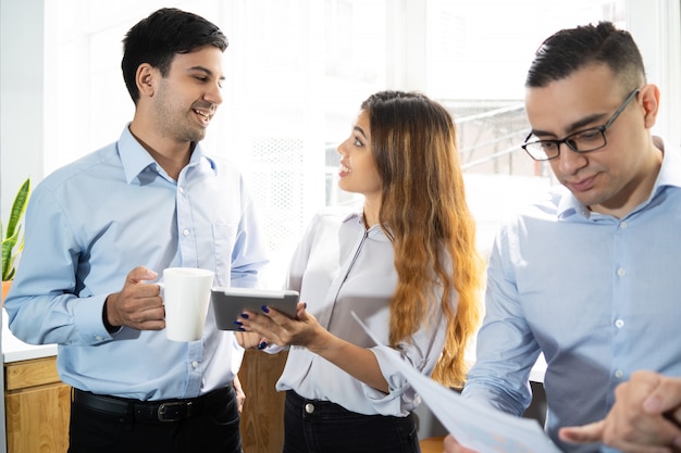 Compañeros de trabajo positivos con la tableta emocionados con la discusión