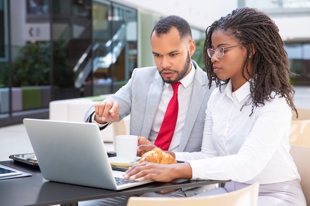 Compañeros de trabajo serios mirando y discutiendo la presentación