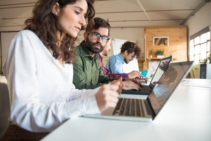 Foto gratuito compañeros de trabajo serios con portátiles discutiendo el proyecto