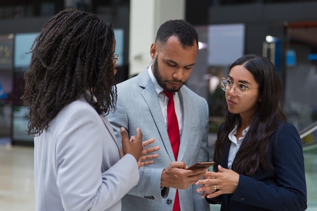 Compañeros de trabajo serios que usan teléfonos inteligentes