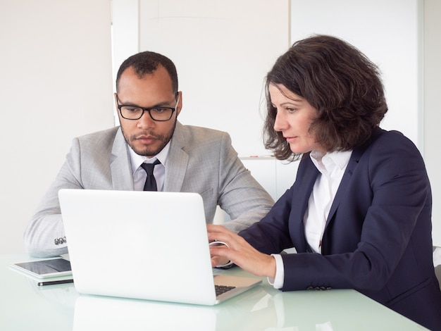 Compañeros de trabajo serios usando laptop