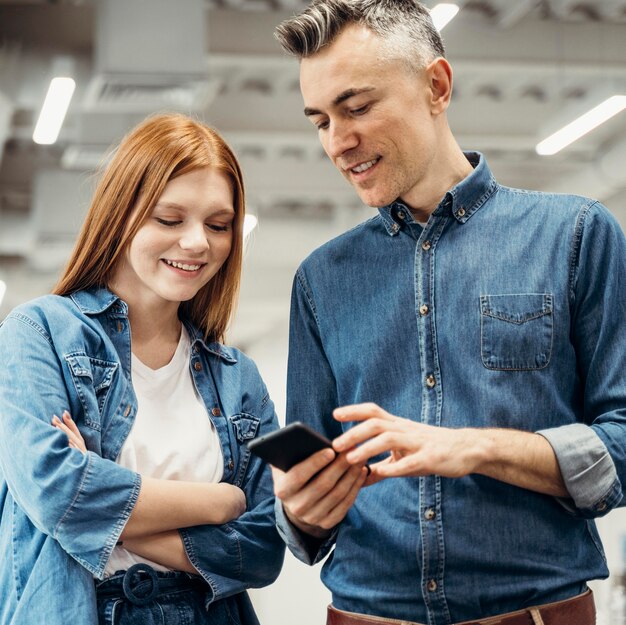 Compañeros de trabajo sonrientes mirando un teléfono