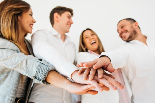 Compañeros de trabajo sonrientes de la oficina que ponen las manos juntas