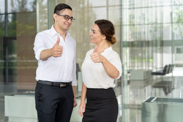 Compañeros de trabajo sonrientes que se miran y expresan su aprobación