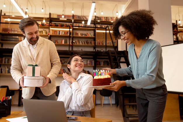 Compañeros de trabajo de tiro medio celebrando con pastel