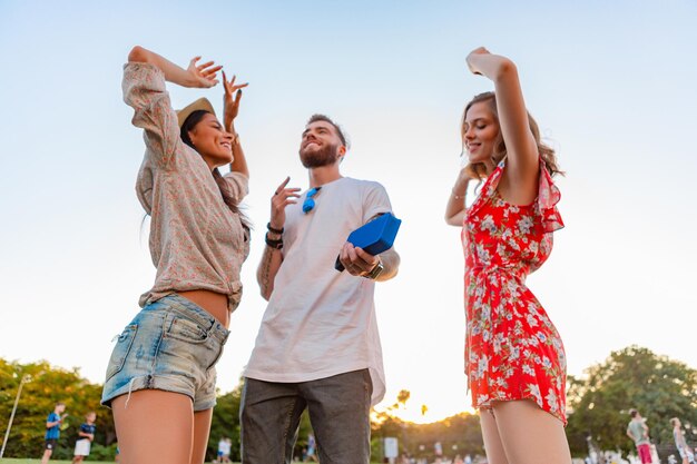 Compañía de amigos divirtiéndose juntos en el parque escuchando música