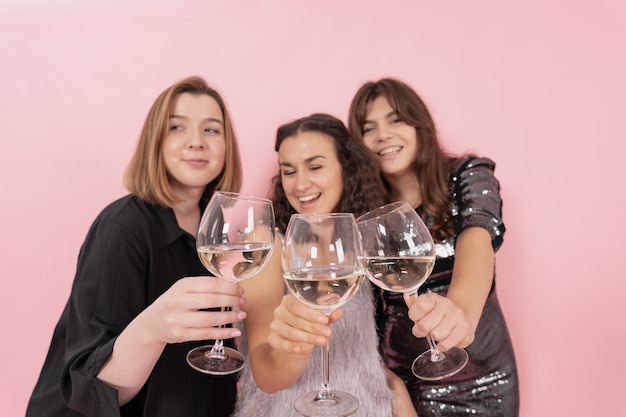La compañía de chicas con copas de champán sobre un fondo rosa