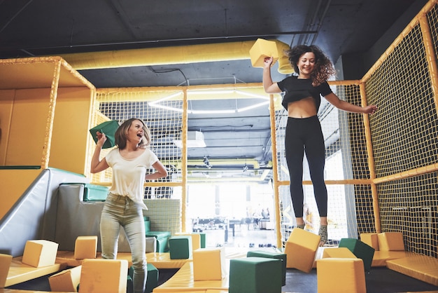 La compañía es una mujer joven que se divierte con bloques suaves en un parque infantil en un centro de trampolines.