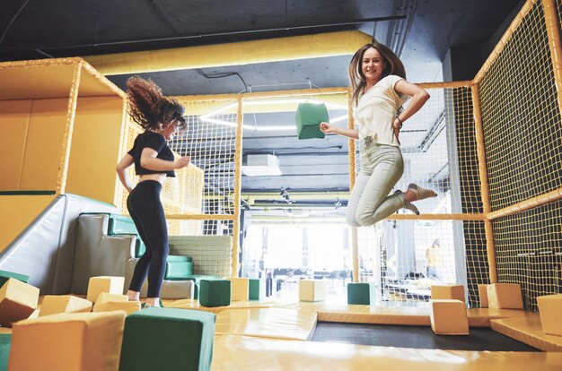 La compañía es una mujer joven que se divierte con bloques suaves en un parque infantil en un centro de trampolines.