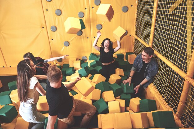 La compañía es una mujer joven que se divierte con bloques suaves en un parque infantil en un centro de trampolines.