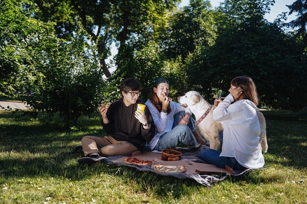 Compañía de hermosos jóvenes almorzando al aire libre. Concepto de comida rápida.