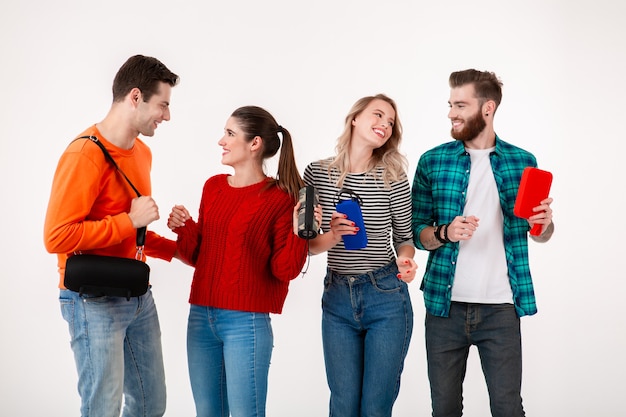 Compañía joven inconformista de amigos divirtiéndose juntos sonriendo escuchando música en altavoces inalámbricos, bailando riendo