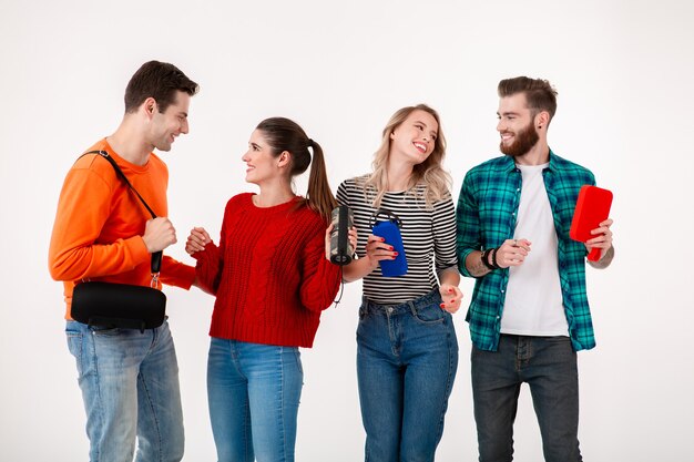 Compañía joven inconformista de amigos divirtiéndose juntos sonriendo escuchando música en altavoces inalámbricos, bailando riendo