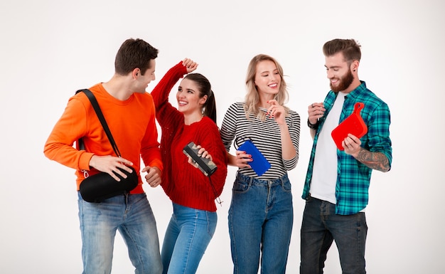 Compañía joven inconformista de amigos divirtiéndose juntos sonriendo escuchando música en altavoces inalámbricos