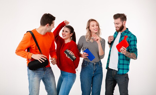 Compañía joven inconformista de amigos divirtiéndose juntos sonriendo escuchando música en altavoces inalámbricos