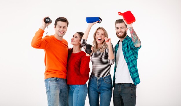 Compañía joven inconformista de amigos divirtiéndose juntos sonriendo escuchando música en altavoces inalámbricos