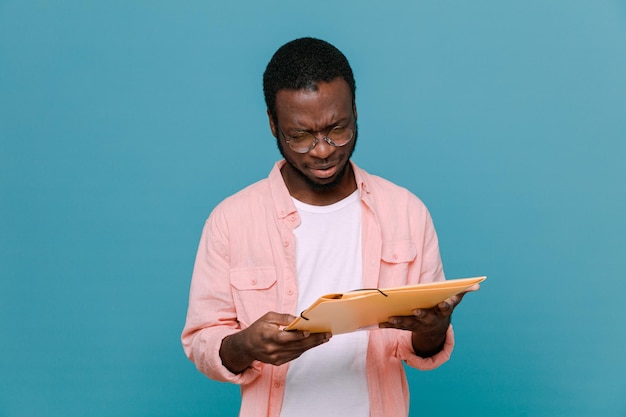 complacido sosteniendo una carpeta joven afroamericano aislado de fondo azul