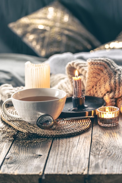 Composición acogedora para el hogar con una taza de velas de té y un elemento de punto