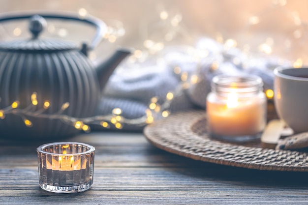 Foto gratuita composición acogedora para el hogar con una taza de velas de té y una tetera